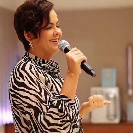 Vair Helena palestrando com microfone em evento corporativo
